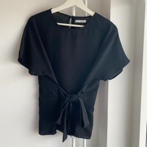 Svart blus - superfin svart blus med knyte i midjan! snyggt att knyta en rosett både fram och i ryggen. strl M men sitter bra på mig som vanligtvis har S 🌈
