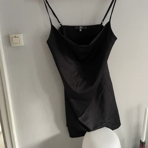 Svart kort satin klänning misguided - Svart kort miniklänning från Misguided med drapering vid bysten, storlek 36, sidenaktigt material. Svår att fånga på bild, kan försöka fota på vid bättre tillfälle, oanvänd.