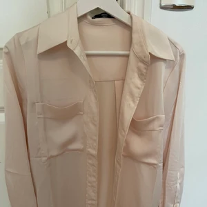 Beige satinskjorta - Beige satinskjorta som jag köpt på mango. Silkeslent material. Passar även en storlek S trots att det är XS. Lite längre skjorta, kommer strax över rumpan för mig som är 164