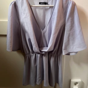 Boohoo blus i ljusblått - Ljusblå blus med urringning och volang nertill. Sparsamt använd och i väldigt gott skick.