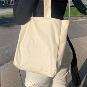 Beige tygväska - Tjocka band, två fickor på isnidan som passar perfekt för vattenflaskor (se vår instagram aia.revuse för mer detaljer) och basyta. Den är väldigt bekväm att bära eftersom tyget är stadigt. Banden är bredare och gör den enklare att ha över axeln. Tillverkar denna utefter intresse, så om du vill köpa, så syrs en.