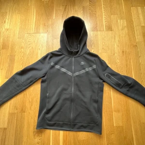 Nike tech fleece-svart - Svart Nike tech fleece och i barnstorlek Xl. Nästan oanvänd och köpt för 2 veckor sen för ungefär 900 kr. Inga hål eller skador på tröjan utan i bra skick. Vill sälja den eftersom den är för stor för mig. Kontakta mig om du vill lägga bud eller så!💪🏼🍾