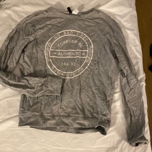 Grå långärmad tröja - Grå långärmad tröja med tryck.