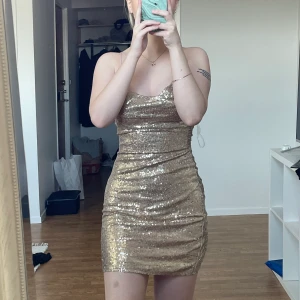 Guldig paljettklänning stl 34 - Säljer denhär urfina klänningen från Nelly i stl 34, tyvärr kom den inte till användning nå mer än 1gång. Så derför säljer jag den till nån som har mer användning för den💗 jag är 162cm för referens Kunden står för frakt 