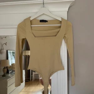 Långärmad body från pretty little thing storlek XS - Säljer denna beige långärmade bodyn från plt, använd en gång och är i storlek XS (uk 4). Köparen står för frakt! 💗 