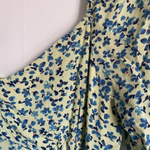 Klänning - Gulblommig klänning i storlek 40. Nästan aldrig använd, nyskick.  Har dragkedja på baksidan och slits på ena sidan. 