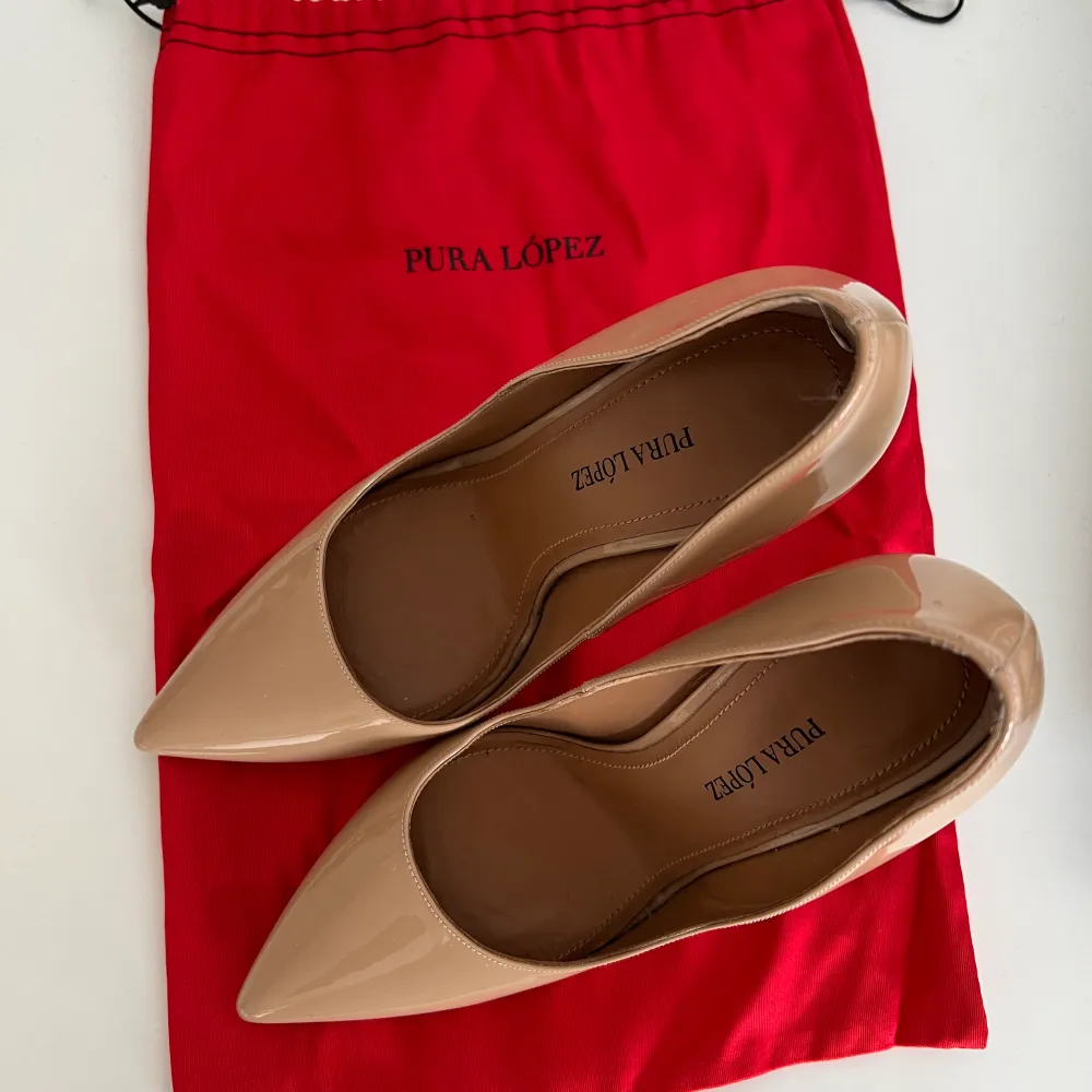 Pura López klassiska designer pumps i storlek 38 (lite små i storleken så passar säkert någon som har 37). Bara använda 2 gånger. Äkta läder, tillverkade i Spanien. Klackhöd 11cm. Den röda tygpåsen är givetvis inkluderad i köp! Fint skick! Nypris: 1600kr. Kengät.