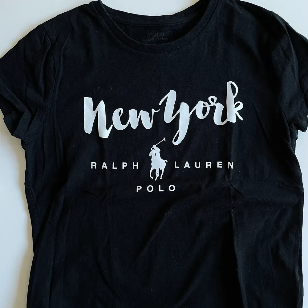 Svart T-shirt med vitt tryck från Ralph Lauren i storlek XS. Pris 100 kr eller högstbjudande. Fint skick.. T-shirts.