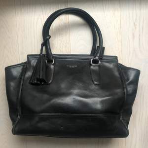 Timeless spacious black leather Coach bag that has been fairly used and show signs of aging (scratches on leather, discoloration)