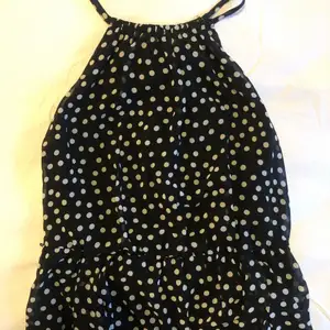 Beautiful airy summer dress with white polkadot pattern and halter neckline. The dress is slightly shorter in front optically prolonging legs when worn.