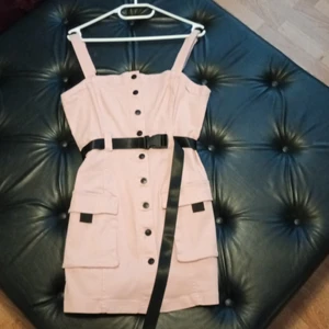 Klänning M - Säljer en rosa  klänning med svart bälte o detaljer i strl 42, mer som 38/40. Endast provad.