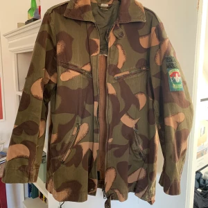 Kamouflagejacka  - En ungersk kamoflagejacka. En välanvänd jacka men generellt bra skick! Schysst size på kragen, många fickor och avslappnad passform 