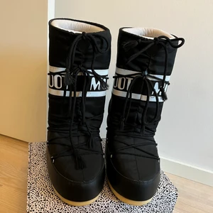 Moonboots - Svarta Moonboots med vita ditaljer i den höga modellen. Dom är i storleken 39-40 och är som nya. 