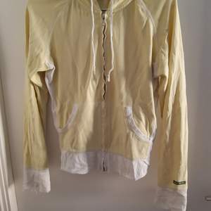 Gul zipup huv tröja med vita detaljer i storlek M. Sliten. Säljer för 50 kr + frakt