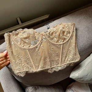 Bustier/bralette - Bustier/bralette från Zara. Köptes förra året och är helt oanvända. Har prislapp kvar. Fin, blommig spets i beige/brun färg. Köpte för 399 på zara hemsida. Knäppning baktill med tre olika ”nivåer” (se bild)