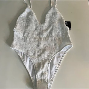 Vit baddräkt  - Vit baddräkt från Nelly. Aldrig använd.  Storlek XL.  Köparen står för frakten.