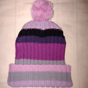 Stickad randig mössa (med tofs/boll) - Stickad mössa i fina färger. Sparsamt använd. Det finns en tillhörande tofsboll som man enkelt kan sy fast, om man vill. Köp nu, annars är fraktpriset 36 kr. 
