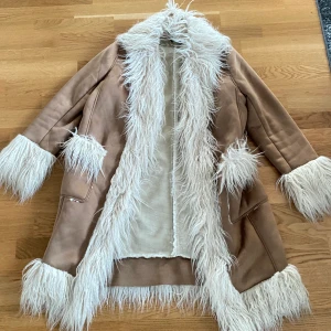 Jacka i mocka  - Ljusbrun jacka i mocka med pälsfoder från ASOS. Storlek 40. Är lite liten i storleken. Endast använd en gång. Helt slutsåld på asos. Jackan går ner till knäna på mig och är 173 cm. Pris går att diskutera. 🫶köparen står för frakt.