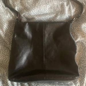 Svart läderväska med bruna detaljer. Har ett litet märke på ena sidan men annars i bra skick! Köpt secondhand.