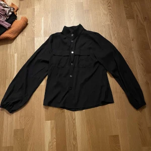 Två fina blusar - Två fina blusar, den ena svarta är med knappar , den andra är en gul med siden tyg och en snörning längst midjan. 