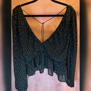 Crops topp - Svart prickig magtröja med Vringad. Bra skick använd två gånger och har en diskret volang form i nedre delen av toppen 