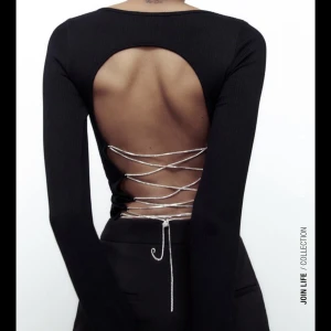 Festlig topp Zara - Festtopp från zara. Svart tight i skönt material med öppen rygg och jättefin strass i bak. Helt oanvänd endast testad! Prislapp kvar. Det står storlek M-L men jag tycker 100% att den är som en storlek S