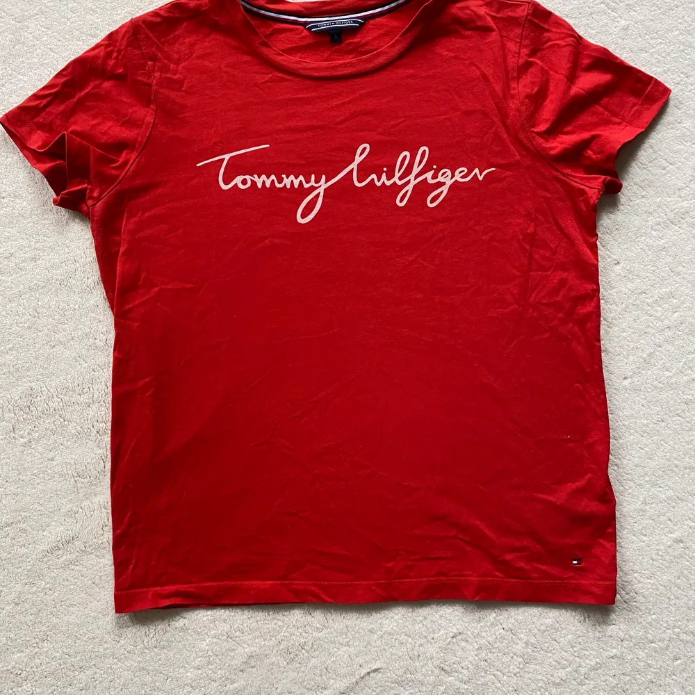 Röd Tommy Hilfiger t-shirt med vitt tryck🫶🏻 jättesnygg men färgen passar inte mig💕 så gott som ny då den ej har kommit till användning. T-shirts.
