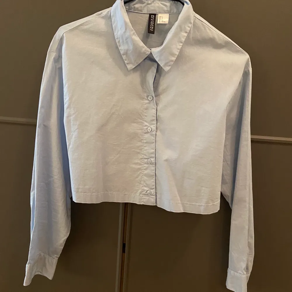 Ljusblå croppad skjorta från H&M.  Använd fåtal gånger.  Storlek S men passar bäst en 34.  Ord pris 99kr. Skjortor.