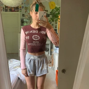 Långärmad croppad tröja - Långärmad croppad tröja med vinröd färg och ljus rosa ärmar, stort vitt tryck på framsidan samt rött tryck längst höger arm och blått längst vänster. 100% organic cotton 