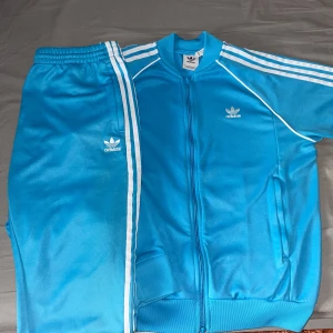 Adidas sett - Det här sättet är i ganska bra skick och är använd inte så ofta Max 10 gånger och den här inga skador. Byxorna är i storlek XL och tröjan är storlek L. Skriv till mig om du vill ha den så fort som möjligt. Köpte den för 1600kr och säljer för 1000kr.