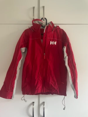 HH jacka - Helly Hansen vindjacka i storlek s Finns en liten däcka på jackans nedre del (bild 3)