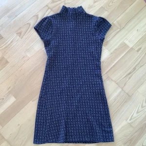 Klänning - Det är en svart klänning med silvriga mönster på. Det är storlek M ungdom. Den är nästan helt oanvänd.