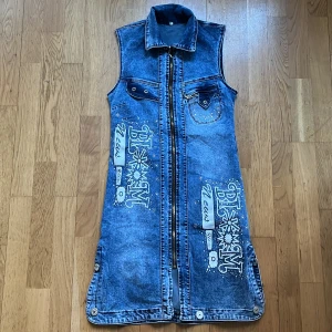 Denim klänning  - Kort klänning i jeanstyg m strassdetaljer och dragkedja i mitten. Massa stretch i tyg, sitter tajt på stl S (38). 