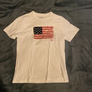 Ralph Lauren T-shirt - Ralph Lauren T-shirt Vit Slitningarna på den Amerikanska flaggan är original  Bra skick, använt ett fåtal gånger
