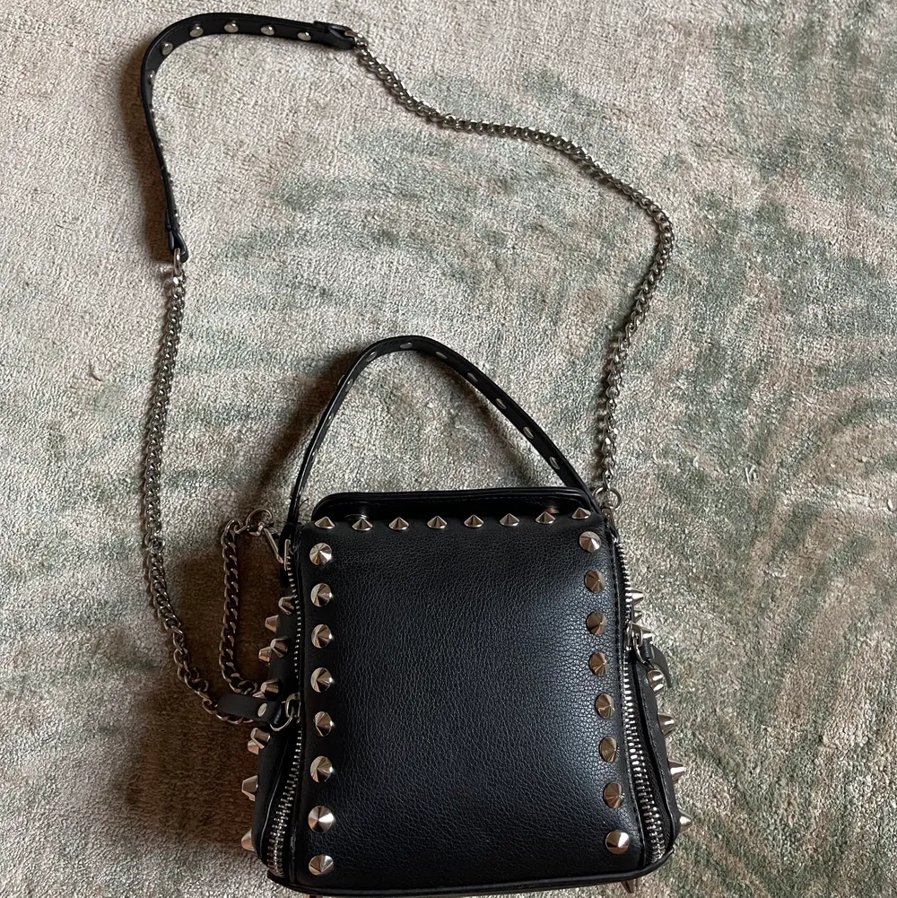 Säljer den populära och coola nitväskan från Zara. Väskan har två innerfack och en lång kedja till som man kan ha crossbody. . Väskor.