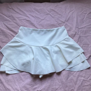 Vita kjolshorts - Vita kjolshorts i storlek M. Perfekta för de som vill ha en kort kjol men inte vill stressa över att vinden ska få den att blåsa upp. Volangerna gör också så att man ser kurvigare ut!