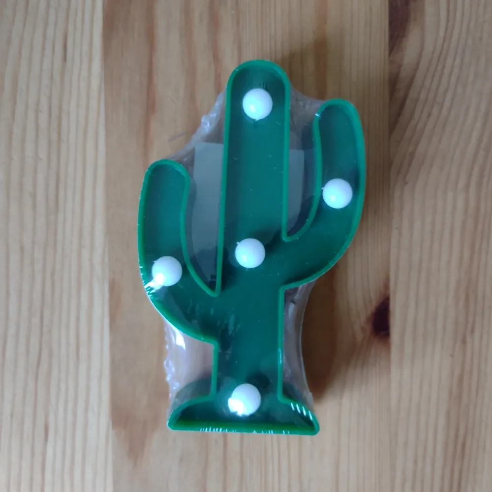 Dekorationsbelysning. Grön kaktus, ca 12 cm hög. Fem små led-lampor. Batterier medföljer. Oanvänd och inplastad.. Övrigt.