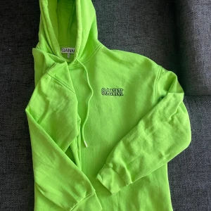 Limegrön GANNI Hoodie - Säljer denna Limegröna Hoodien från GANNI som köptes förra hösten i CPH. Den är i ytterst gott skick, med inga märken eller tecken på slitage. Har enbart används ett fåtal gånger.