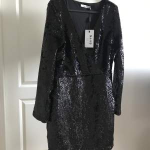 Långärmad svart Mini Dress med paljetter och overlap från NA-KD, perfekt inför nyår 🤩 Dragkedja vid sidan, helt oanvänd med lappar på🏷