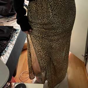 En lång tunn kjol med leopard mönster och en slits på vardera sida (en på höger och en på vänster sida). Det finns en svart tunn underkjol som gör att ingen syns igenom och att det känns behaglig och bekväm att h på sig alltid