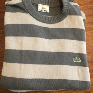 Tröja Lacoste  - Randig, stickad tröja från Lacoste. Passar srtl S-M. Sparsamt använd.