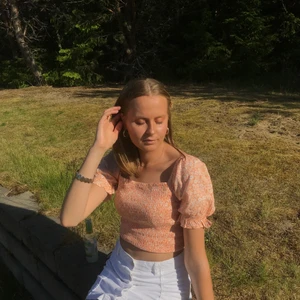 Sommrig topp - Somrig topp med blommigt mönster i aprikos och vitt. Den är använd men fortfarande i bra skick.