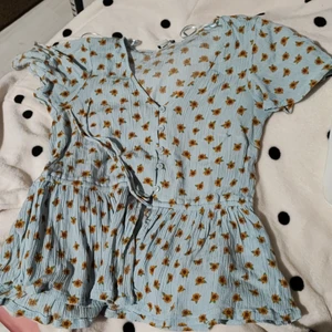 Blommig blå blus - Söt topp, ljusblå med solrosor. Storlek 38. Fin kvalité