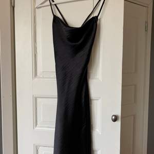 Fin klänning i satin med justerbara axelband och öppen rygg! Den är använd en gång och är som ny!