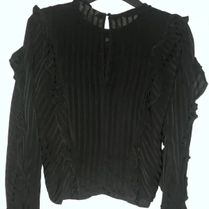 Volangblus - Fin skir blus. Volanger framtill och längs med armarna. Ser likadan ut med volangerna på baksidan som på framsidan. Använt sparsamt.