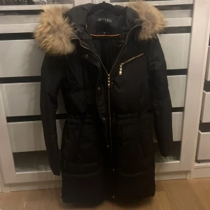 Hollies jacka  - Hollies jacka i lång modell. Nyligen köpt men tyvärr för stor för mig, oanvänd. Äkta pälskrage. Köpt för 4699kr. Pris kan diskuteras 