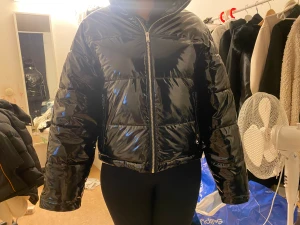 Svart croppad puffer jacket - En svart glansig jacka ifrån Gina tricot i super fint skick helt oanvänd.