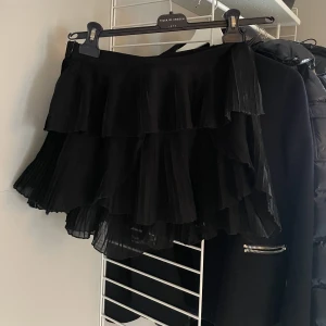 kjol - Svart kjol med gömda shorts inuti. En volang har lossnat lite, men det går att fixa med nål och tråd super lätt! 