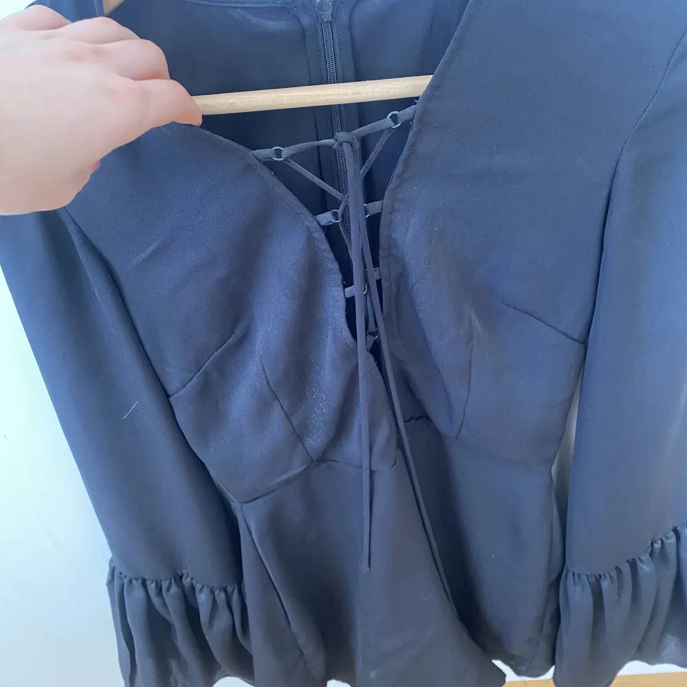 Säljer denna jumpsuit i svart från NAKD. Den har lite knytningar vid brösten och är väldigt bekväm så man kan både klä upp och klä ner den. Den är i lite silkes polyester material. Blusar.
