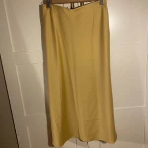 Silkeskjol - Gul silkeskjol från Lindex (midi), använd en gång, nypris 299kr. Dragkedja i midjan, samt resår. Frakt tillkommer!!!!